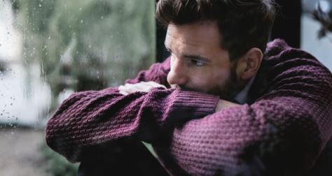 Sad-looking young man looking out a window